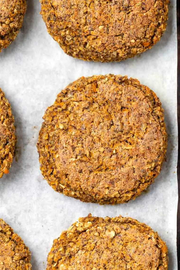 Overhead close up view of butternut squash white bean burger patties on a parchment-lined baking sheet.