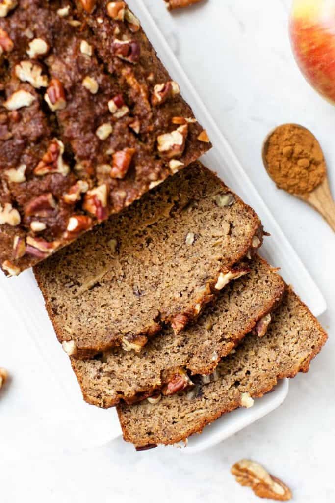 This gluten-free apple banana bread recipe is made with high-protein almond and quinoa flours, apples, and cinnamon for a cozy fall treat! Overhead view of an apple banana bread loaf cut into slices.