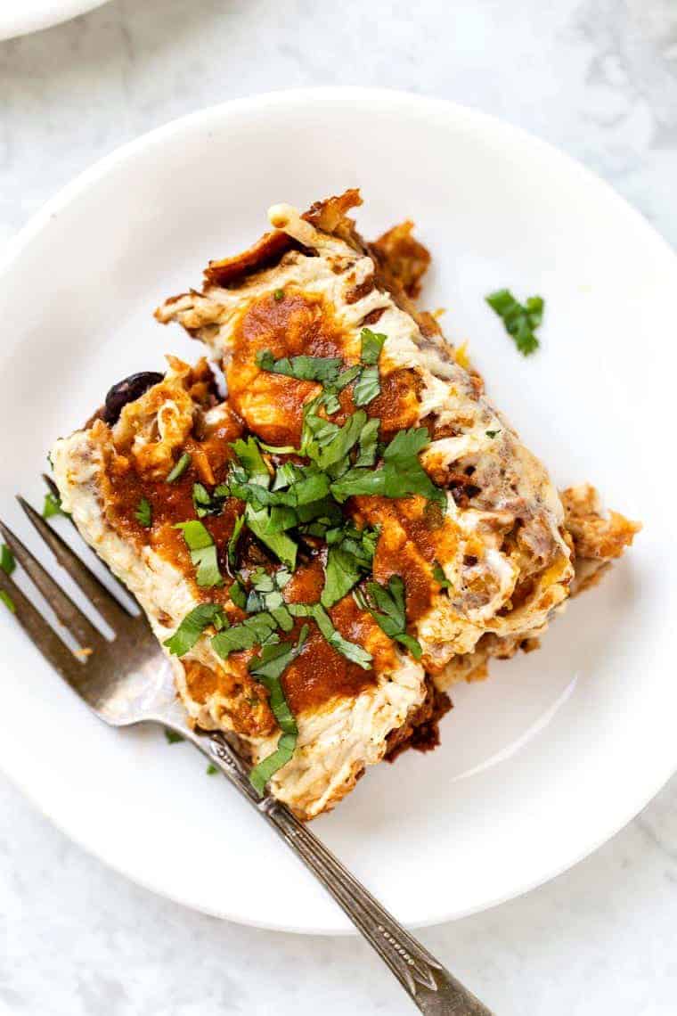 These amazing vegan black bean enchiladas also have butternut squash and a homemade enchilada sauce. They're easy, flavorful, and gluten-free! Vegan enchiladas on a white plate