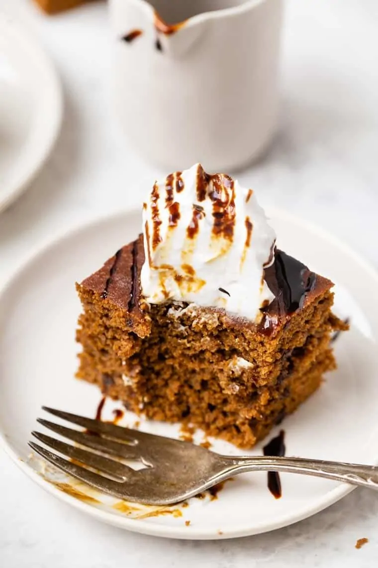 Gluten-free gingerbread cake on plate with fork topped with coconut yogurt and molasses drizzle