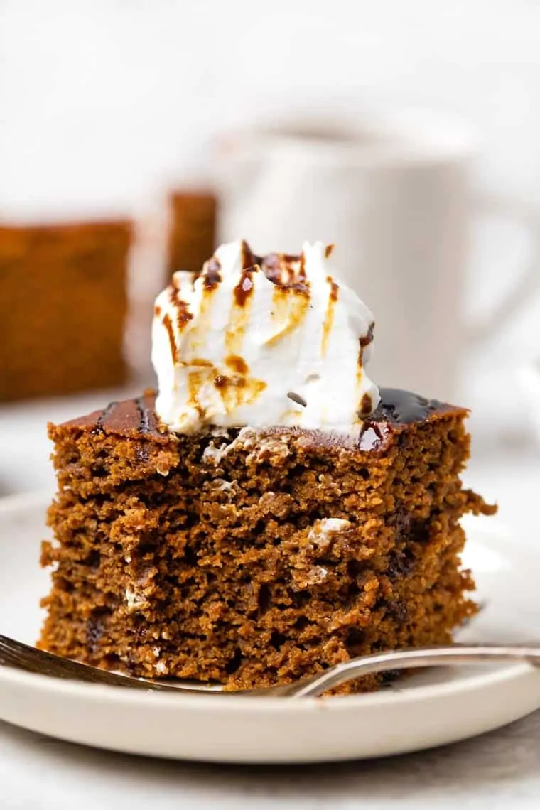 White plate with piece of healthy gingerbread cake topped with coconut yogurt