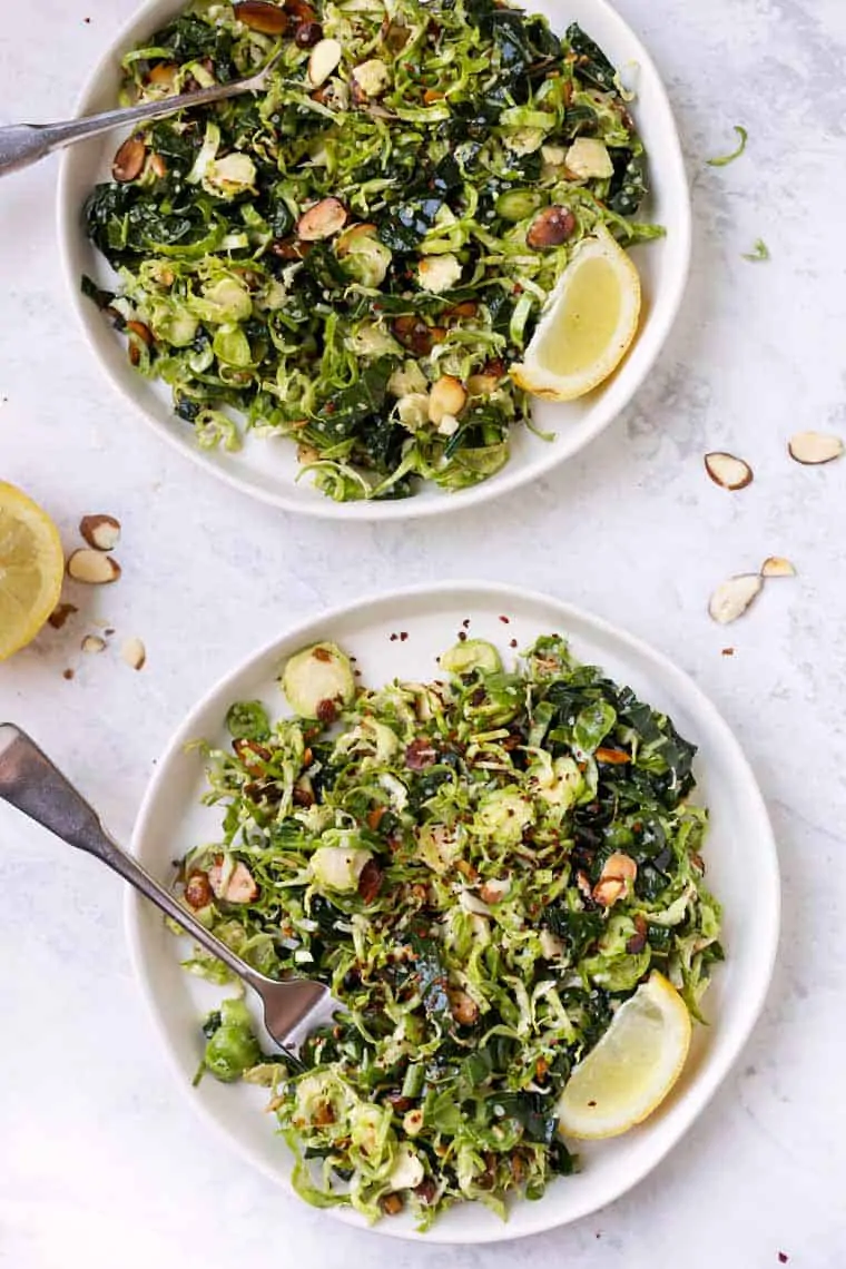 Overhead view of shaved Brussels sprout salad on two plates with forks