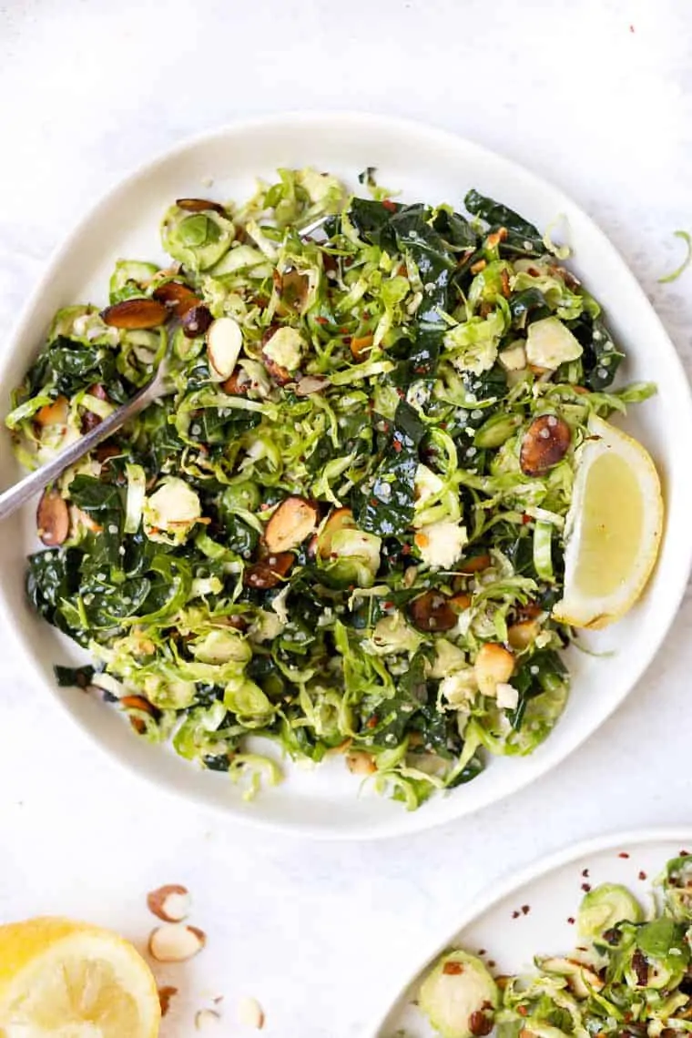 Best Brussels Sprout Salad on white plate with lemon wedge and fork