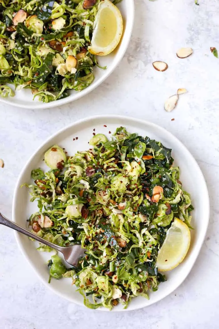 Overhead view of two plates of shaved Brussels sprout salad