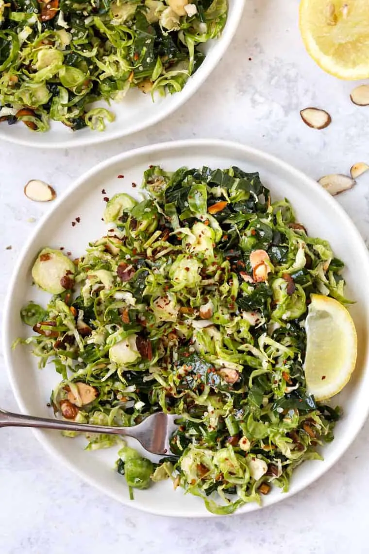 This shaved Brussels sprout salad is easy and tasty! A great side, but can also be topped with your favorite protein for a heartier meal. Top down view of shaved Brussels sprout salad on plate