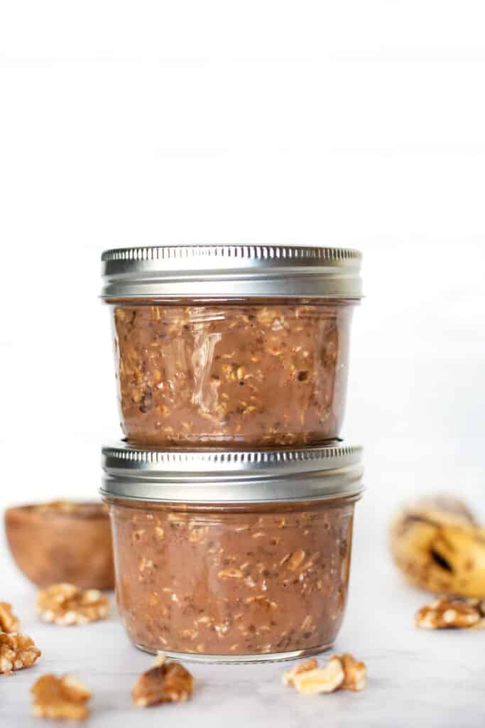 Chocolate overnight oats are an easy breakfast that tastes like dessert! These chocolate oats are vegan, gluten-free, and great for meal prep. Two jars of chocolate overnight oats stacked.