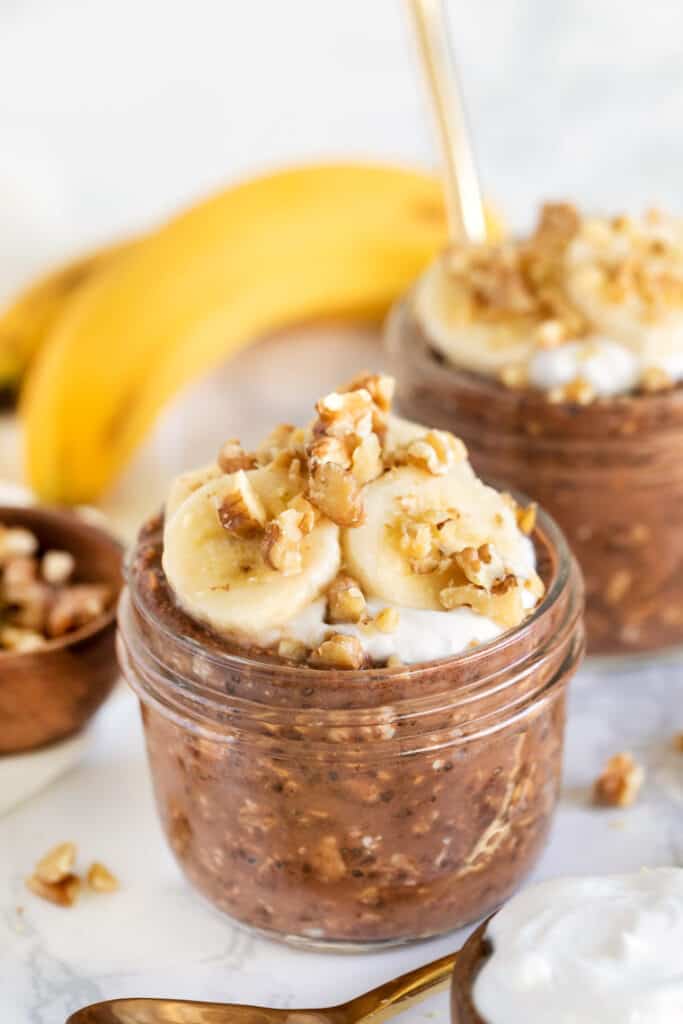 Chocolate overnight oats in small glass jars topped with banana slices.
