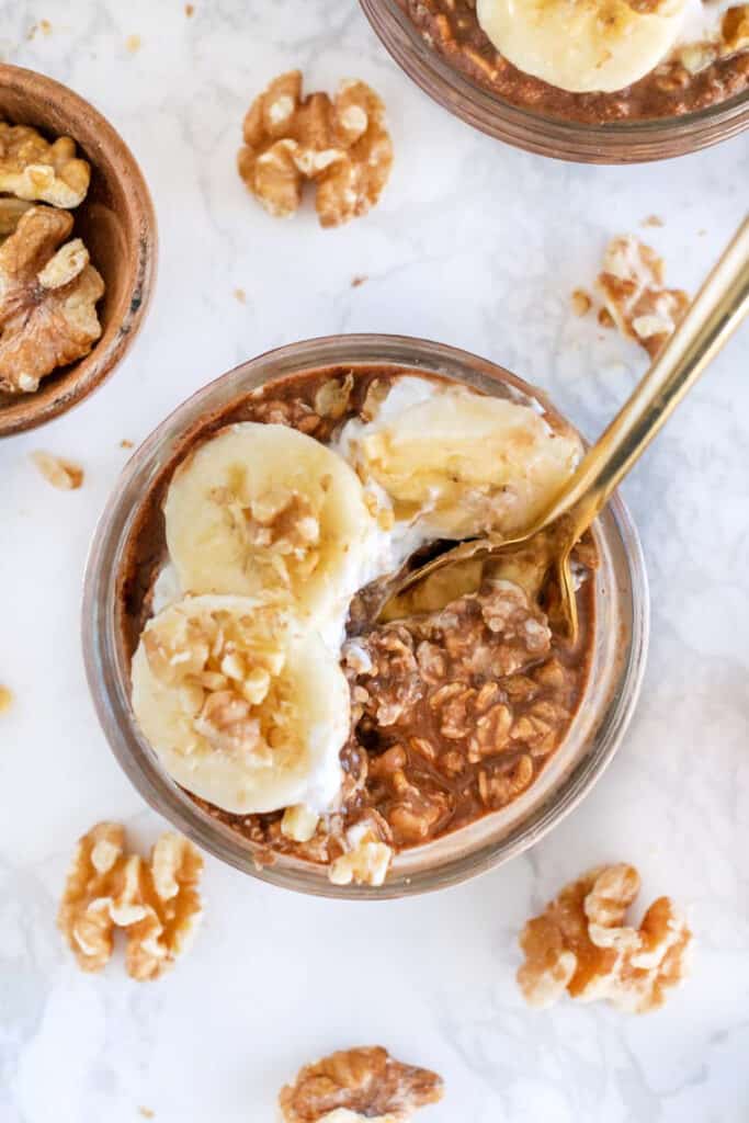 Chocolate overnight oats are an easy breakfast that tastes like dessert! These chocolate oats are vegan, gluten-free, and great for meal prep. Overhead view of chocolate overnight oats in a jar topped with sliced bananas.
