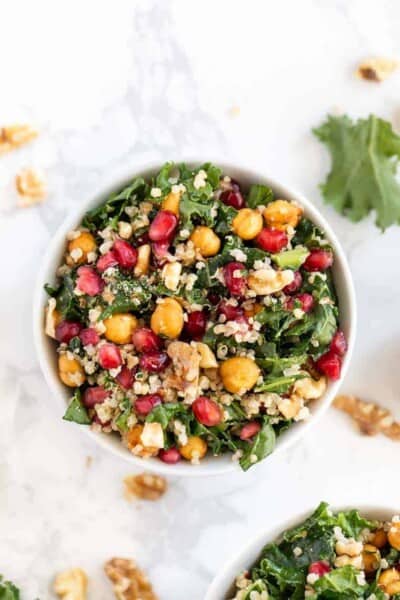 Overhead view of a kale pomegranate salad in a white bowl.