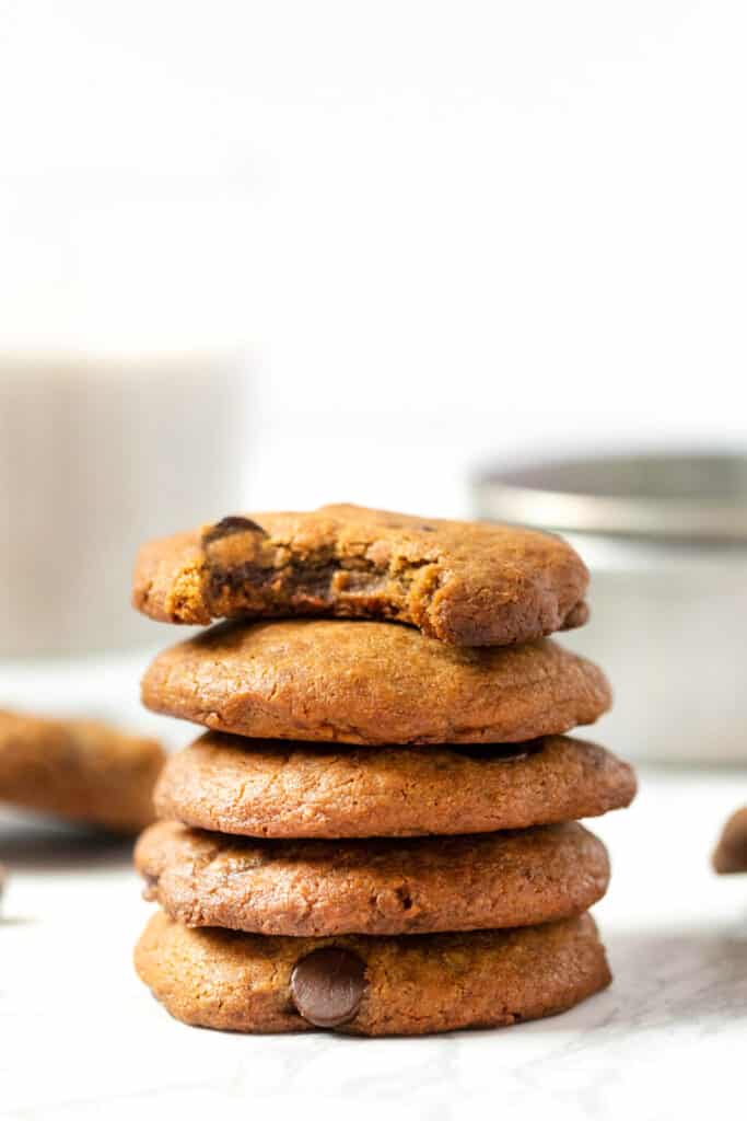 A stack of 5 chocolate chip cookies, one with a bite taken out