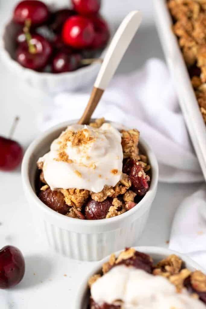 A crumble dessert in a white ramekin with a spoon