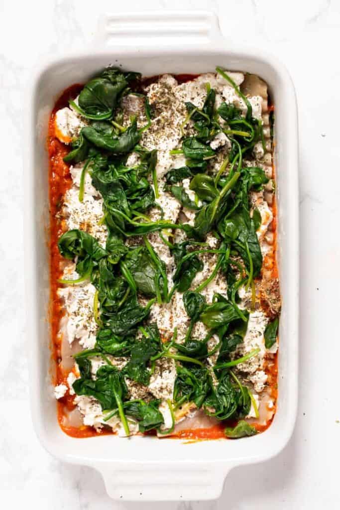 Spinach layered onto lasagna in baking dish.