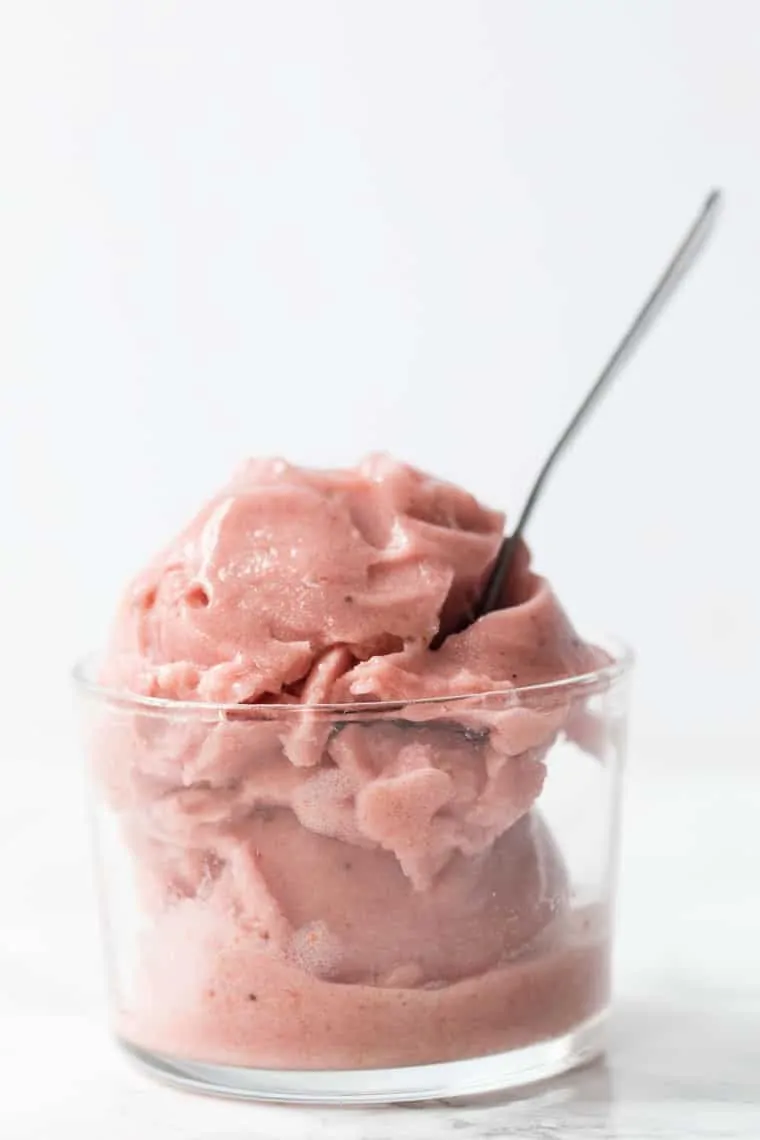 Strawberry banana ice cream in glass bowl with spoon