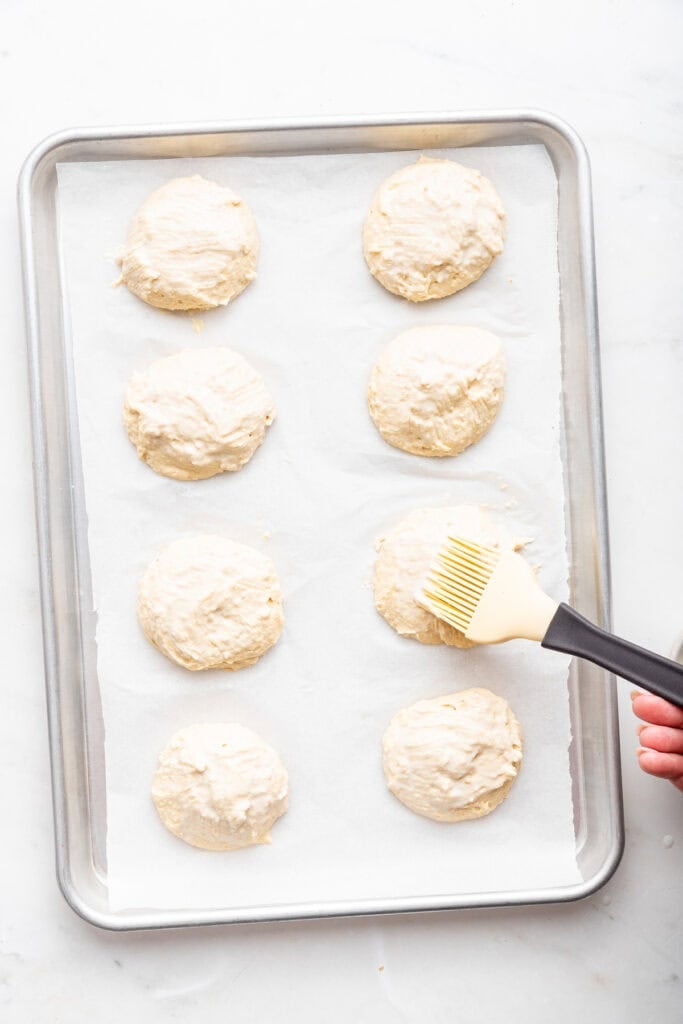 Overhead view of brushing butter onto biscuits before baking