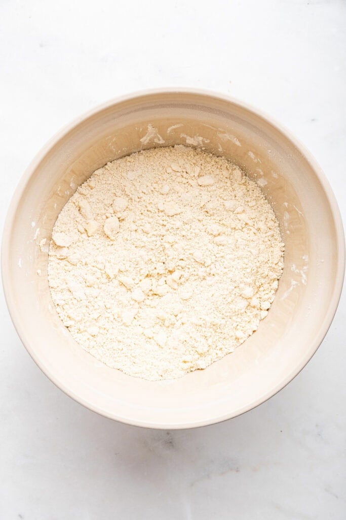 Overhead view of bowl of dry ingredients with butter cut in