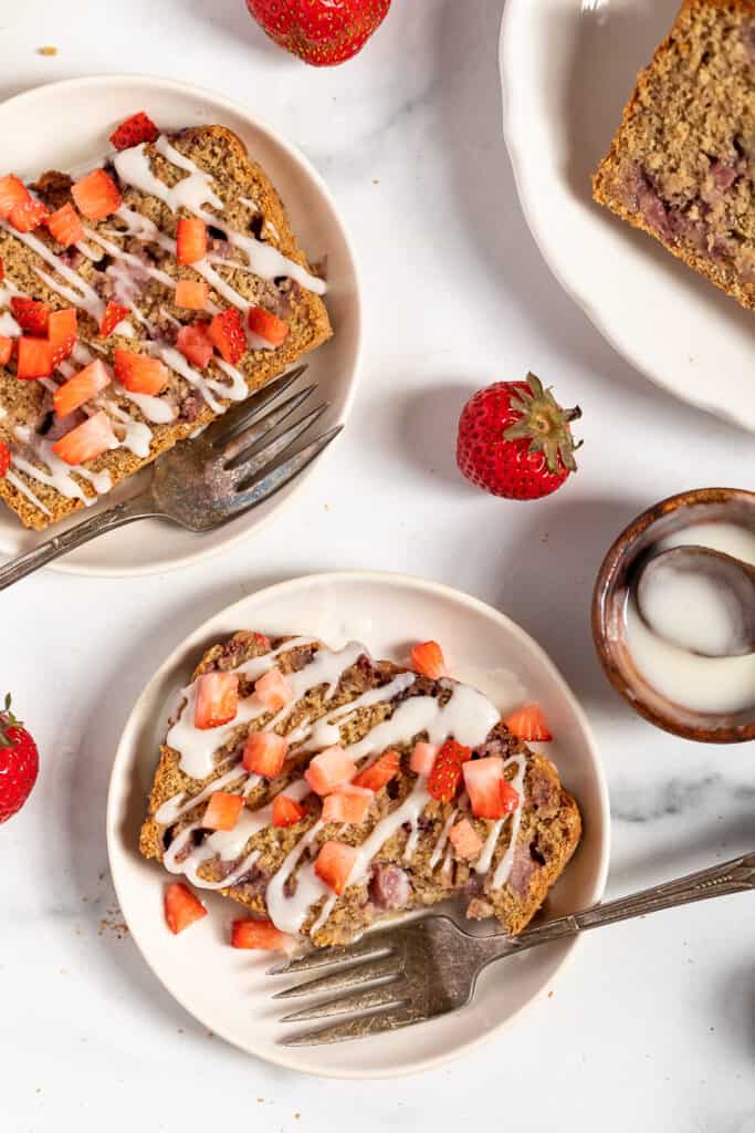 This vegan and gluten-free strawberry banana bread recipe is full of fresh strawberries and sweet banana, without oils or refined sweeteners. Slices of vegan gluten-free strawberry banana bread drizzled with coconut butter and topped with fresh strawberries.