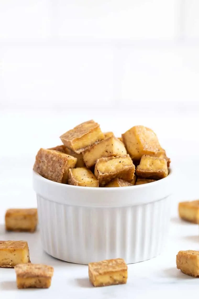 Crispy tofu in white bowl and on countertop