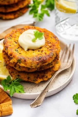 Sweet potato salmon cakes stacked on plate with aioli on top
