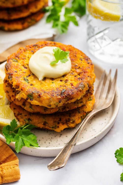 Sweet potato salmon cakes stacked on plate with aioli on top