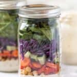 Side view of a sealed mason jar salad with layers of rainbow veggies.