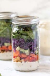 Side view of a sealed mason jar salad with layers of rainbow veggies.