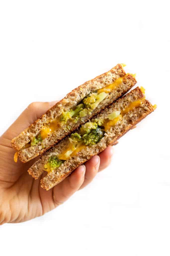 I'll show you how to make a classic vegan grilled cheese, plus easy variations including tomato pesto, broccoli, mushroom, avocado, and more! A hand holding up a broccoli cheddar grilled cheese.