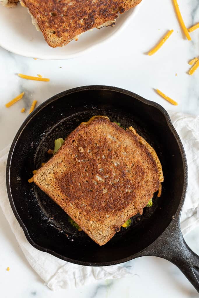 I'll show you how to make a classic vegan grilled cheese, plus easy variations including tomato pesto, broccoli, mushroom, avocado, and more! Overhead view of a vegan grilled cheese in a skillet.