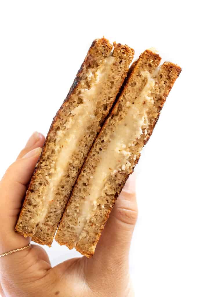 I'll show you how to make a classic vegan grilled cheese, plus easy variations including tomato pesto, broccoli, mushroom, avocado, and more! A hand holding up a traditional grilled cheese.