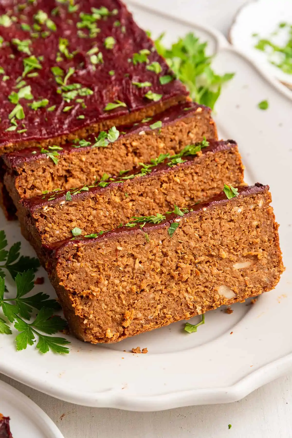 Close up of three slices of vegan meatloaf, with the rest of the loaf behind it