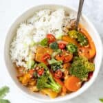 Overhead view of a bowl of tofu red curry served over rice, with a fork.
