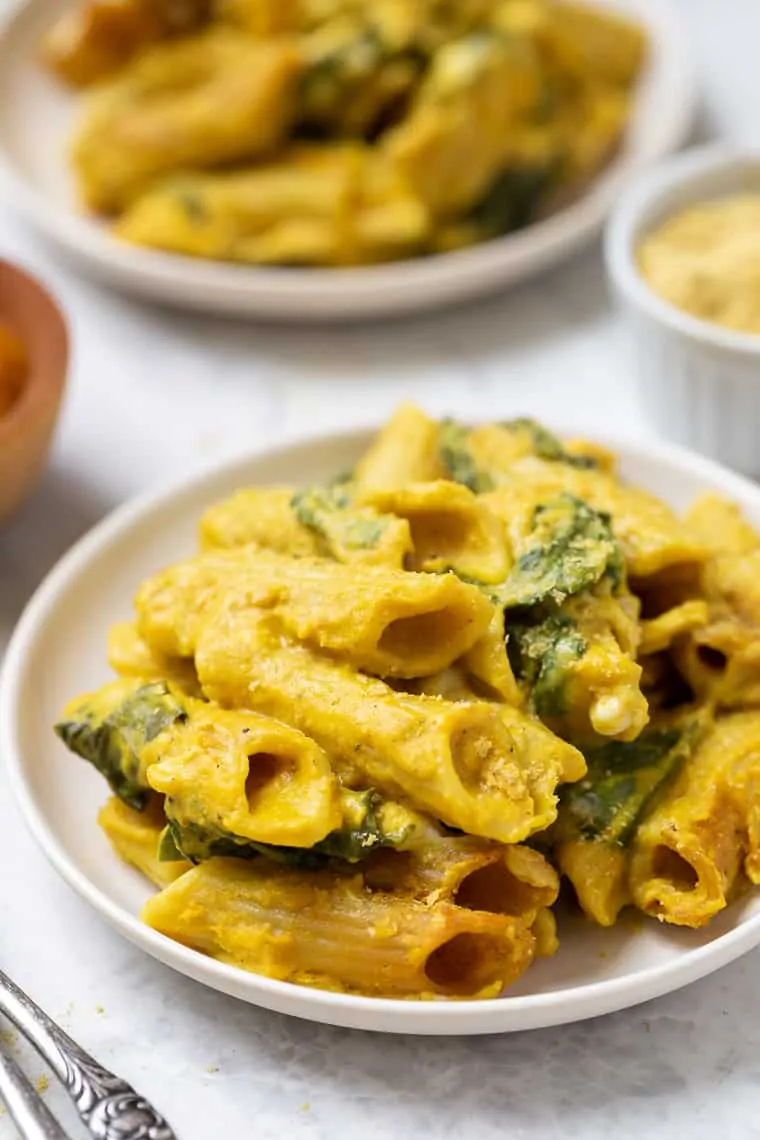 Close up of pumpkin pasta served on a plate with a second plate of pasta in the background.