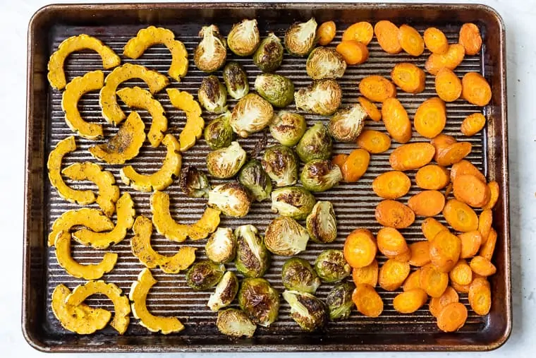 Overhead view of roasted winter vegetables on a sheet pan.