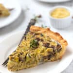 Slice of mushroom quiche on plate with fork