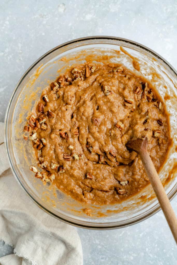 This one-bowl paleo banana bread recipe is easy to make, super moist, and so delicious! It's gluten-free, dairy-free, and refined sugar-free. Paleo banana bread batter in a large glass bowl with a wooden spoon.