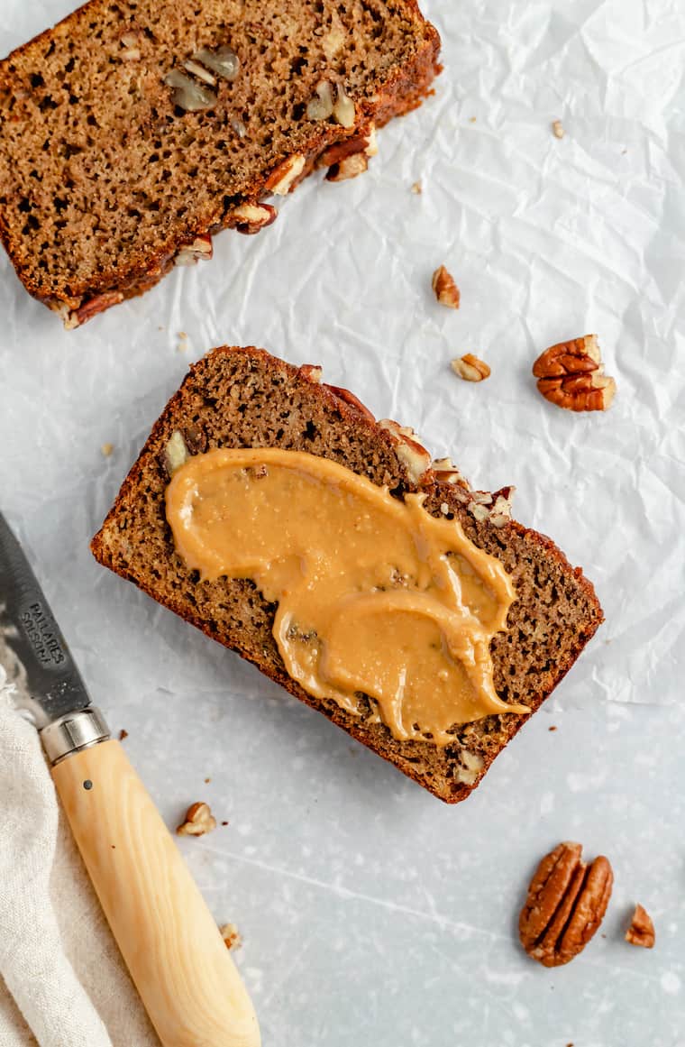 Overhead view of a slice of paleo banana bread spread with peanut butter.