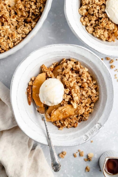 vegan apple crisp with pears and vanilla ice cream in a white ceramic bowl