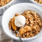 A serving of apple pear crisp topped with vanilla ice cream.