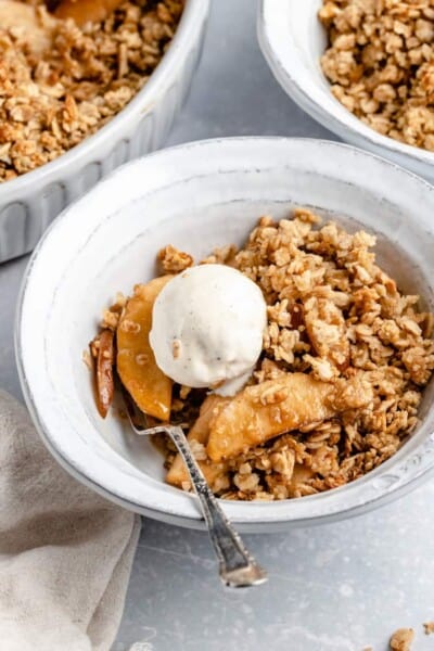 vegan apple crisp with pears and vanilla ice cream in a white ceramic bowl