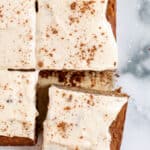Overhead view of gluten-free apple cake frosted with vegan cream cheese frosting, cut into squares.