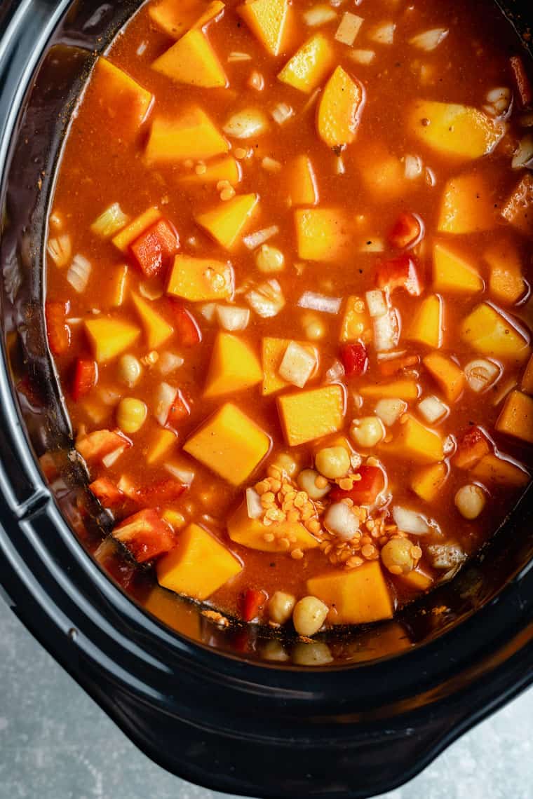 overhead of a black slow cooker with chickpea, lentil and butternut squash stew