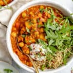 close up on a bowl of slow cooker chickpea soup with coconut yogurt, arugula and quinoa on top