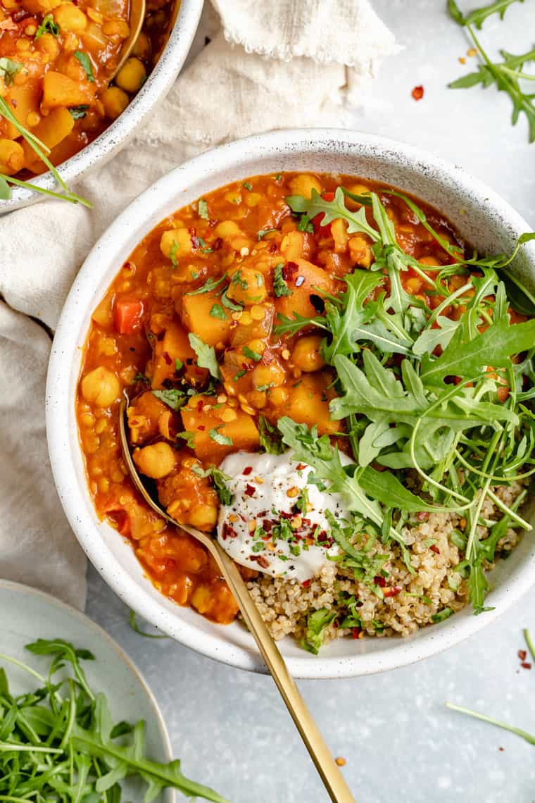 close up on a bowl of slow cooker chickpea soup with coconut yogurt, arugula and quinoa on top