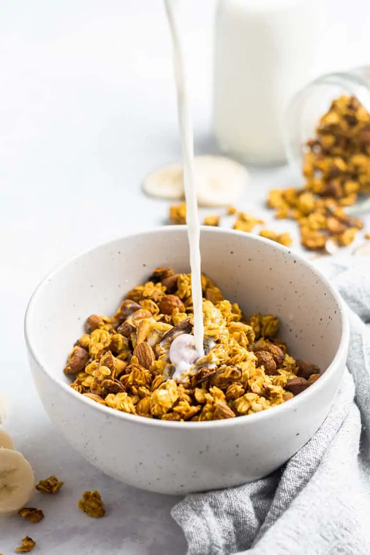 pouring milk into a bowl of turmeric granola