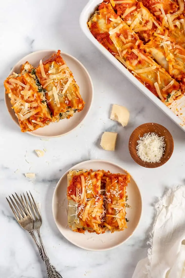 overhead of a table with plates of vegan lasagna roll ups and a baking dish with lasagna