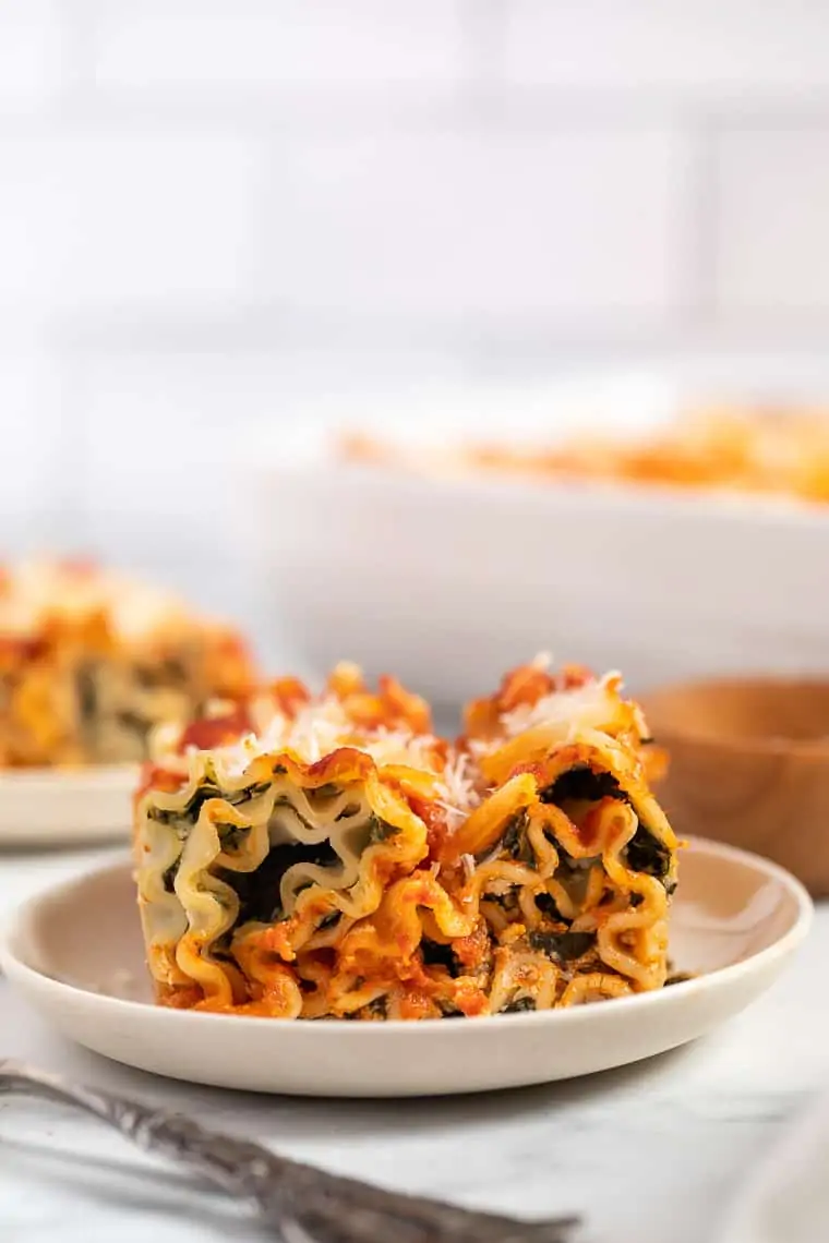 two vegan lasagna roll ups with spinach on a white plate