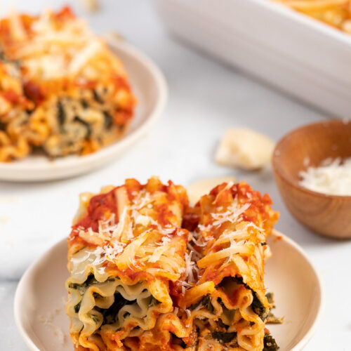 two vegan lasagna roll ups with spinach on a white plate