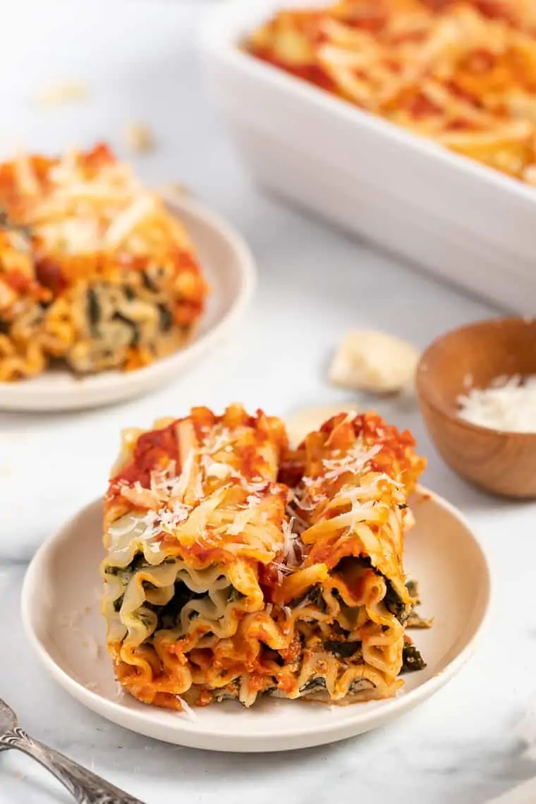 two vegan lasagna roll ups with spinach on a white plate