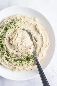 bowl of vegan ricotta with tofu with a spoon and fresh herbs for garnish