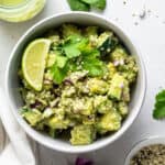 white bowl with cucumber avocado quinoa salad with lime and cilantro