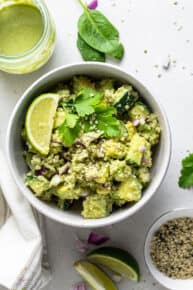 white bowl with cucumber avocado quinoa salad with lime and cilantro